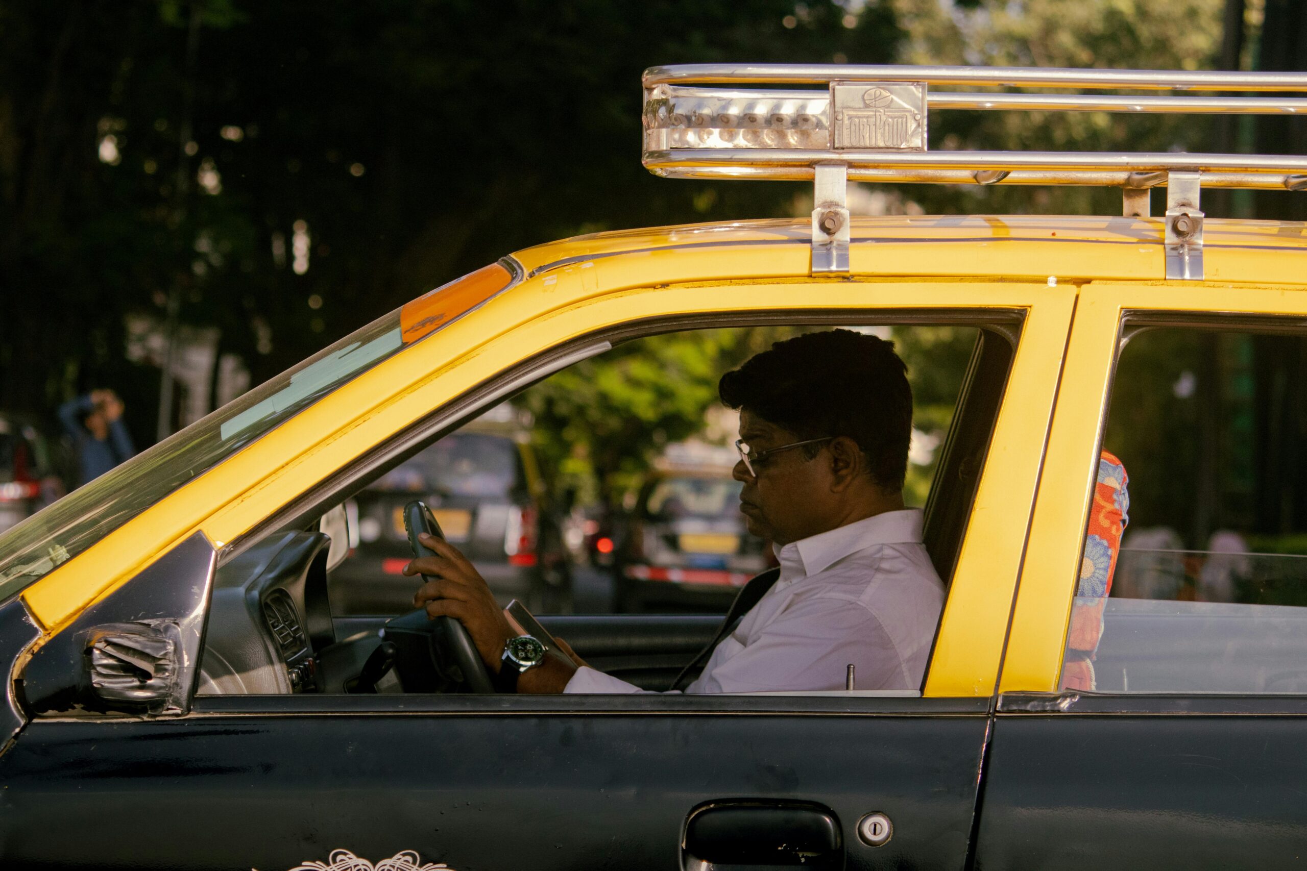 A taxi driver sits attentively in traffic in Mumbai, India, capturing urban life.